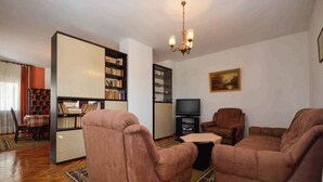 A living room with a sofa set, a television, a bookshelf, and a dining area with a table and chairs. - Holiday apartment with air conditioning and balcony (Premantura)