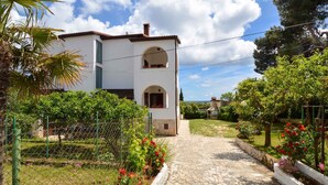 A white two-story house with a central arched window and a small balcony. - Holiday apartment with air conditioning and balcony (Premantura)