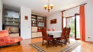 A dining area with a table and chairs, a sofa, a bookshelf, and a chandelier. - Holiday apartment with air conditioning and balcony (Premantura)