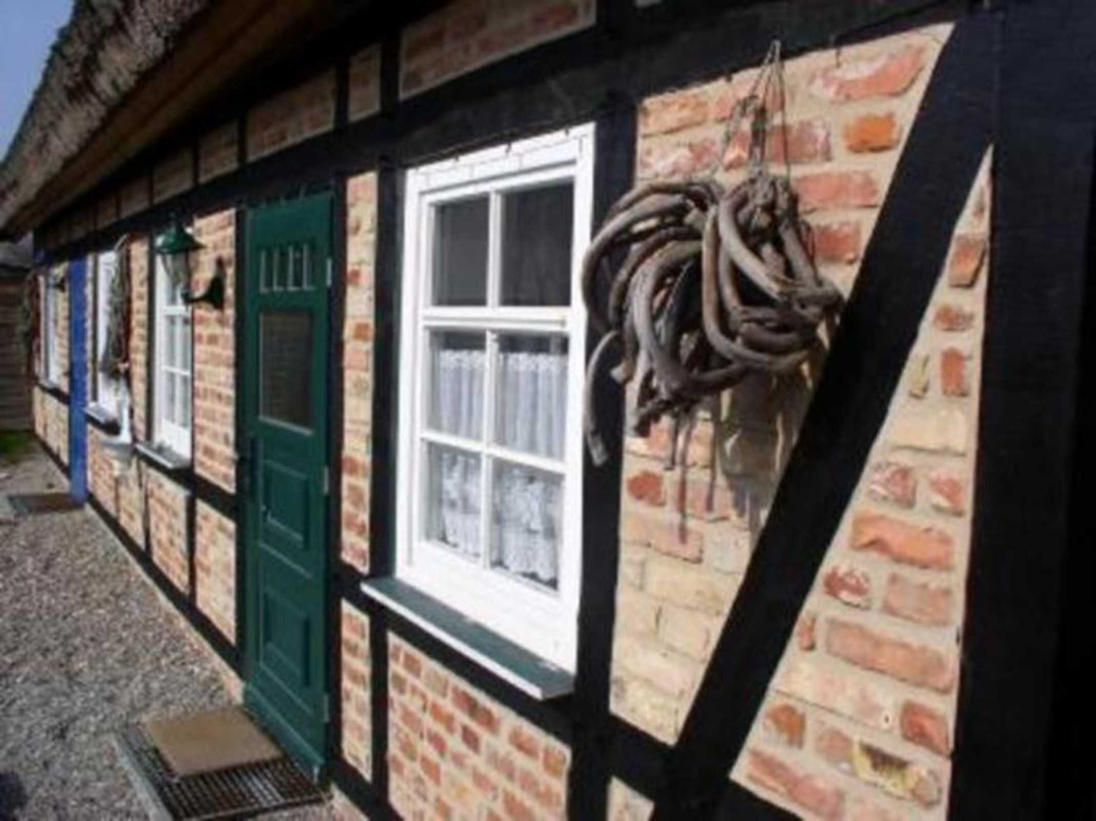 Un bâtiment traditionnel à colombages, avec une porte verte, une fenêtre blanche et des objets suspendus.