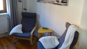 Une pièce avec deux chaises, une petite table, un radiateur et un tableau accroché au mur.