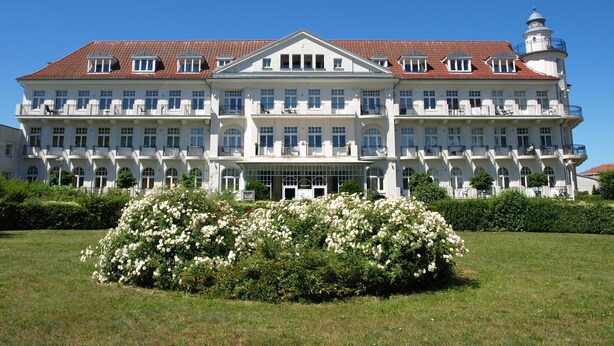 Un grand immeuble à étages, doté d’une façade symétrique, de nombreux balcons et d’une entrée centrale surmontée d’un auvent en verre.
