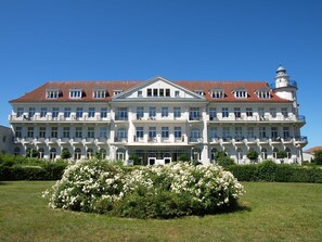 Un grand immeuble à étages, doté d’une façade symétrique, de nombreux balcons et d’une entrée centrale surmontée d’un auvent en verre.