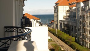 Un balcon avec vue sur la mer, les bâtiments voisins et un ciel dégagé.