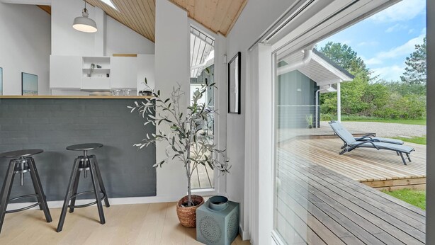 Une cuisine moderne avec des tabourets de bar, une grande fenêtre et une vue sur la terrasse extérieure.