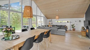 Un vaste espace de vie comprenant une grande table à manger, un canapé gris et une cheminée.