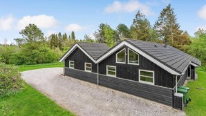 Une cabane à deux étages avec une allée en gravier et une zone herbeuse qui l’entoure.