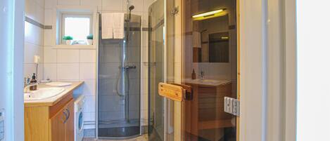 Une petite salle de bain dotée d’une douche à parois de verre, d’un lavabo et d’un miroir.