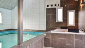 A modern bathroom with a bathtub, a shower area, and a window.