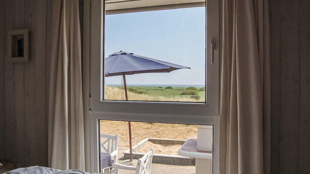 A room with a large window overlooking a grassy field.