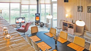 A modern dining area with a long table, chairs, and a television.
