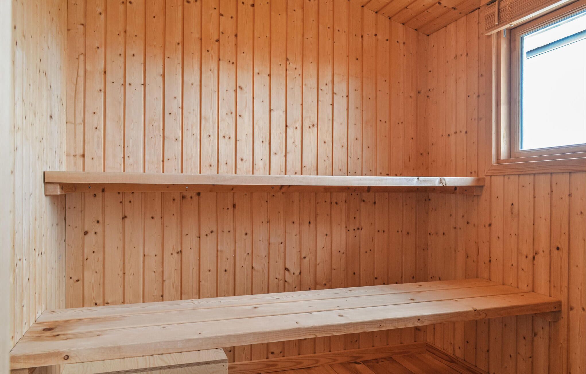 A wooden cabin interior with a bench and a window.