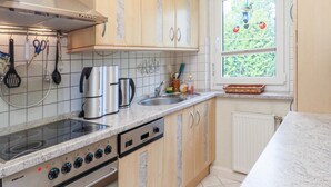 Une cuisine équipée d’une cuisinière, d’un évier et d’une fenêtre.