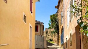 A narrow street with buildings on either side, a gate, and a clear blue sky. - 3 bedroom awesome home in Bédoin (Bédoin)