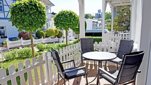 Eine überdachte Terrasse mit weißem Zaun, einem runden Tisch und vier Stühlen.
