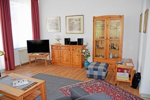 A living room with a television, wooden cabinet, and a sofa.
