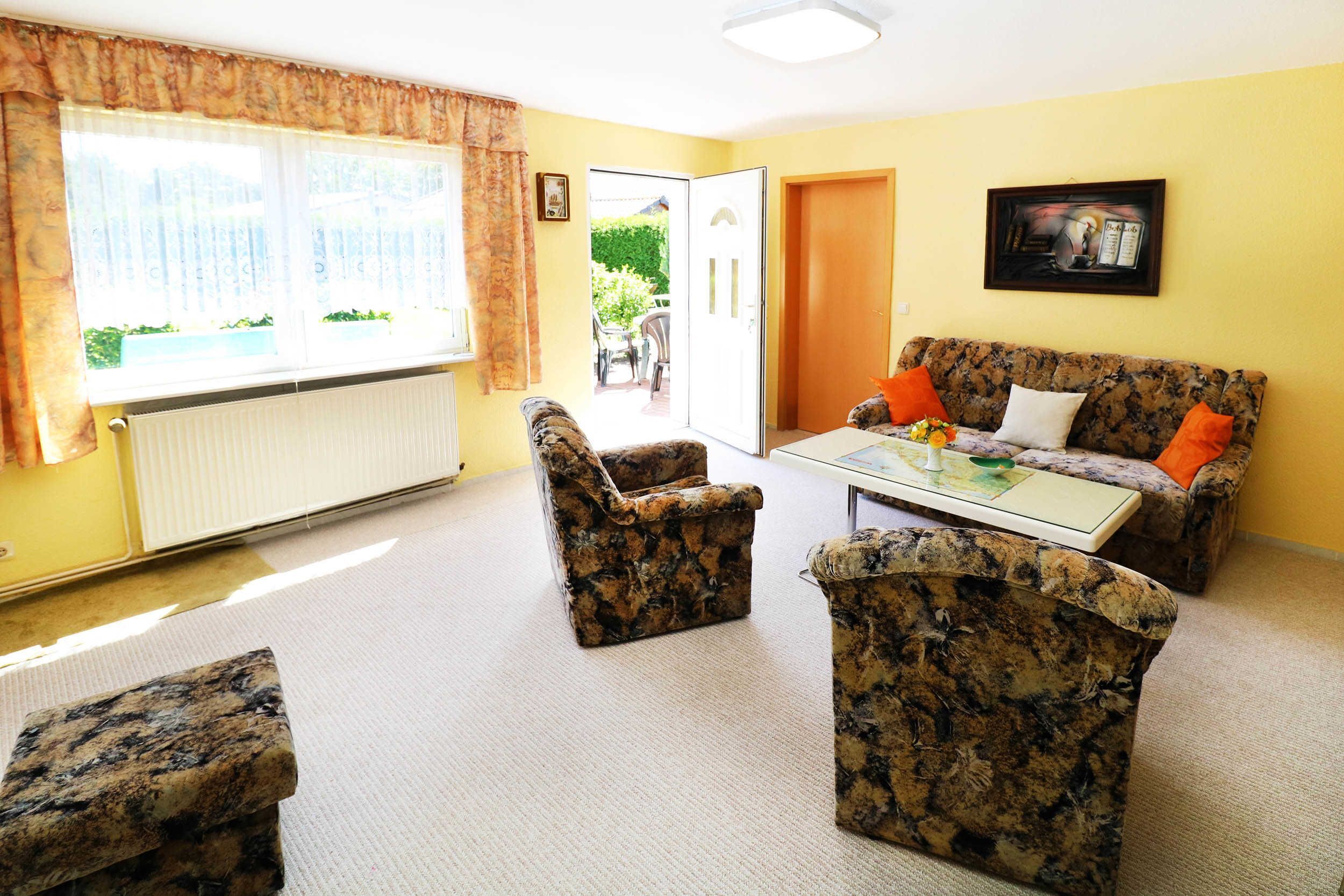 Un salon comprenant un canapé, deux fauteuils, une table basse et un radiateur.