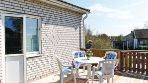 Une terrasse avec une table et des chaises, un mur en briques et une plateforme en bois.