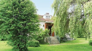 Une maison avec un toit recouvert de tuiles rouges, un porche à l’avant et un escalier menant à l’entrée.
