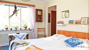 Une chambre confortable avec un lit, une chaise, une fenêtre avec des rideaux, un radiateur et une étagère avec des photos.