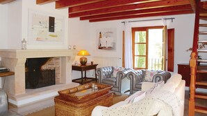 Un salon chaleureux avec une cheminée, un canapé, une table basse et une fenêtre avec des rideaux.