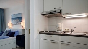 Une cuisine moderne avec des meubles blancs, un plan de travail noir, une machine à café et un évier.