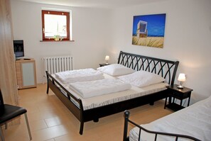 A bedroom with a bed, bedside tables, a chair, a radiator, a window, and a painting on the wall.