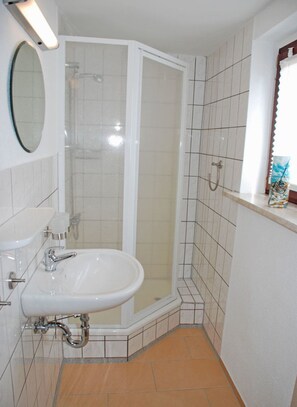 A bathroom with a white sink, mirror, and shower enclosure.