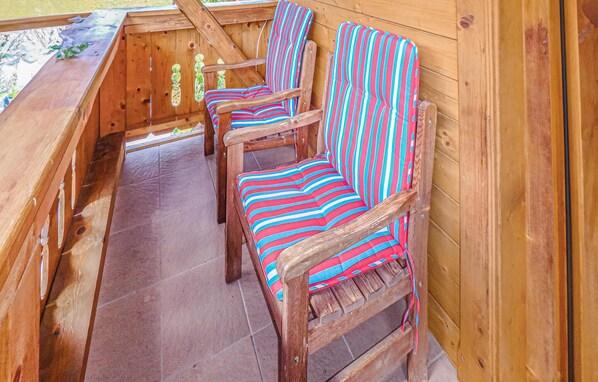 Een houten terras met drie gestreepte stoelen en een houten bank.