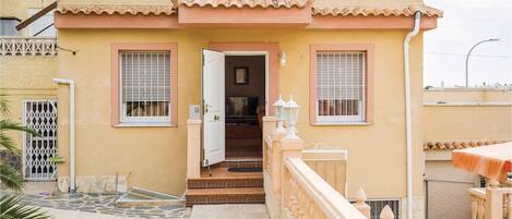 Un bâtiment à deux étages, doté d’un toit en tuiles, d’un balcon avec une balustrade et d’une petite entrée avec une porte.