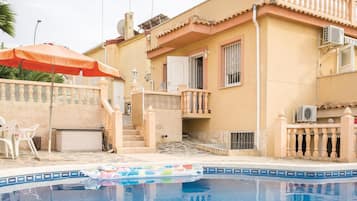 Un immeuble résidentiel doté d’une piscine, de mobilier d’extérieur et d’une antenne parabolique.