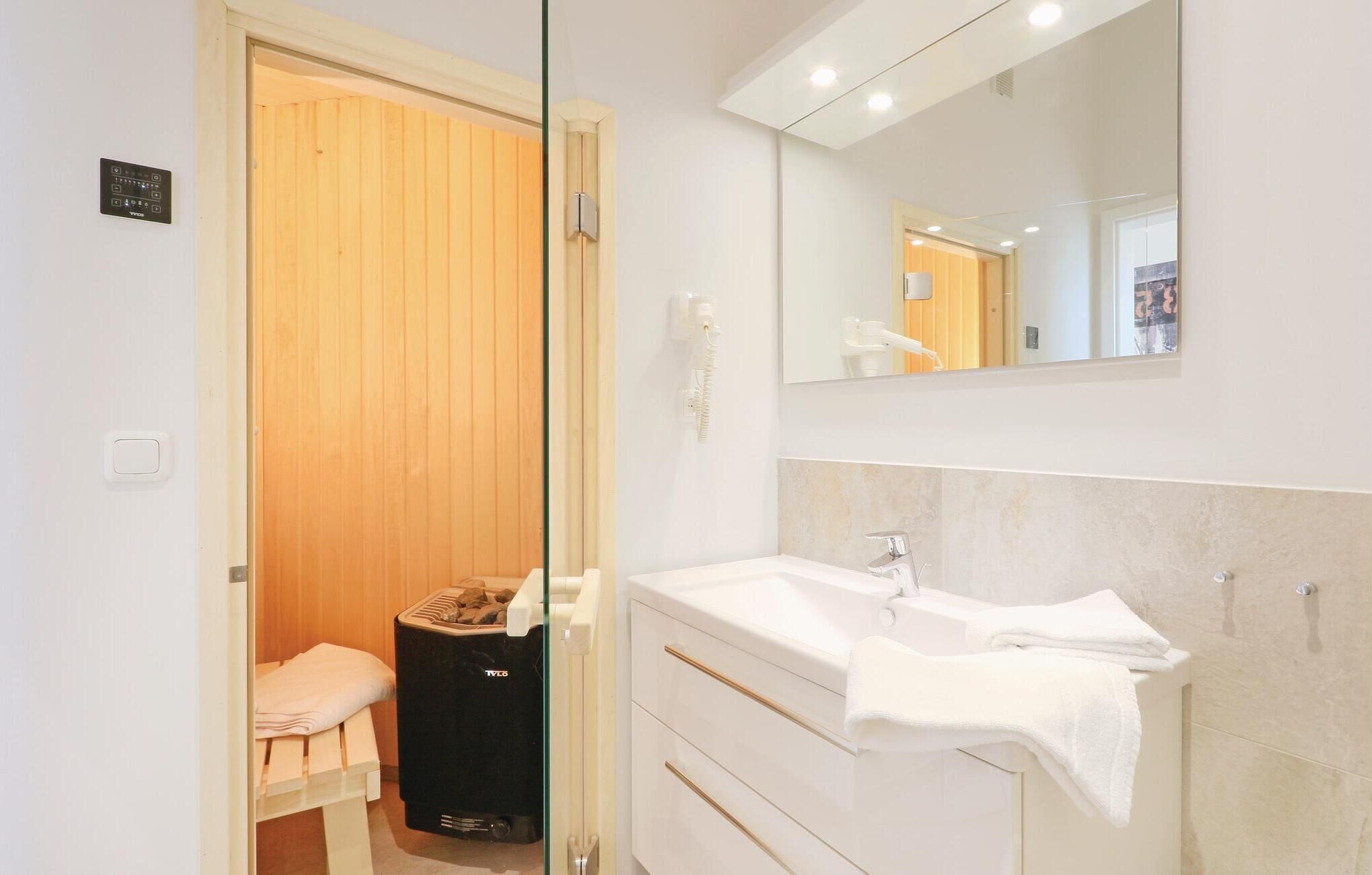 Een moderne badkamer met een houten deur, een wit wastafeltje en een spiegel.