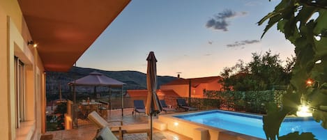 A poolside area with a lounge chair, a covered seating area, and a view of the surrounding landscape.