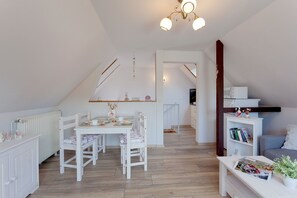 Una habitación acogedora y bien iluminada con una mesa de comedor, sillas, una estantería y una escalera que sube a otro nivel.