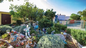 Un jardín con diversas plantas, rocas y una estatua.