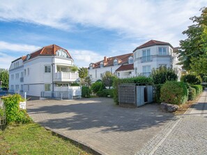 A residential area with white buildings, a paved driveway, and a gated entrance.