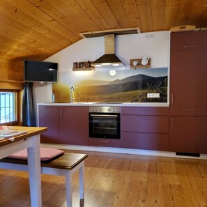 A kitchen with wooden ceiling, a large window, and a painting of a landscape. - FW Haflinger - Hof Roßruck (Fischbachau)