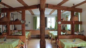 Un espace repas agrémenté de poutres en bois, de nappes vertes et de chaises en bois.