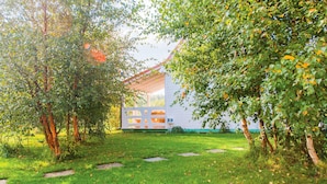 Un bâtiment blanc coiffé d’un toit rouge, entouré d’une végétation luxuriante et d’une pelouse bien entretenue.