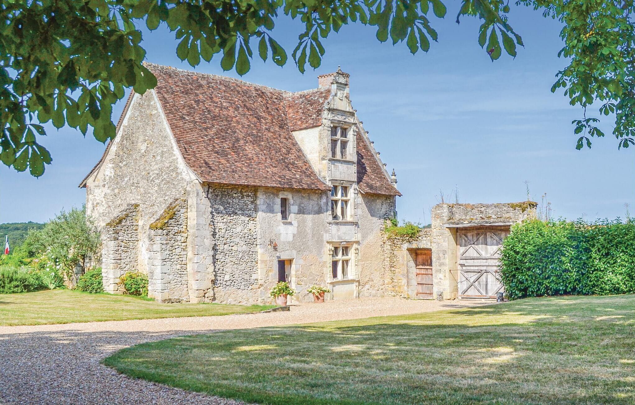 Un bâtiment en pierre avec un toit en tuiles, une petite dépendance attenante et une allée gravillonnée.