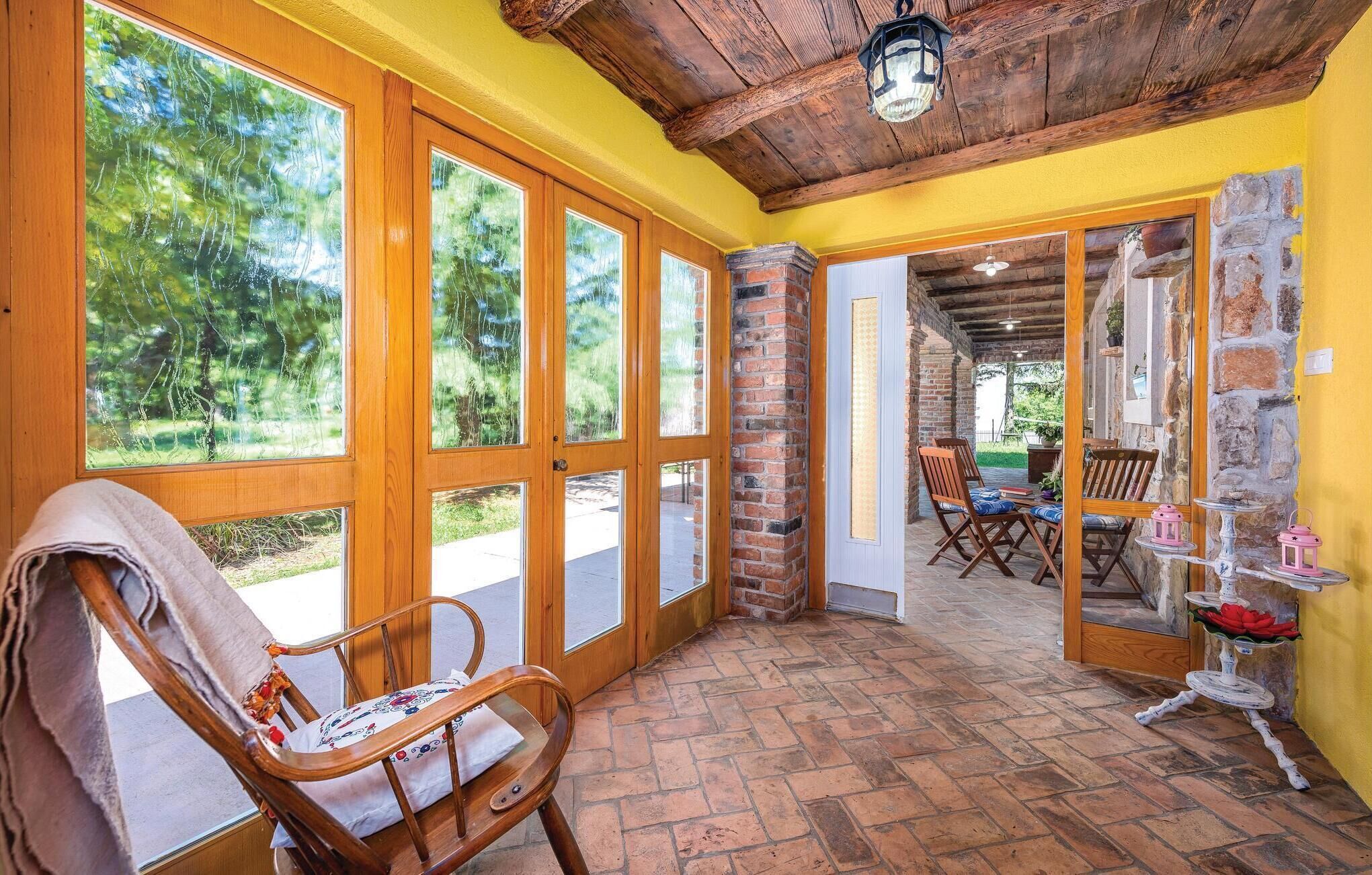 A room with large windows, a wooden ceiling, and a brick wall.