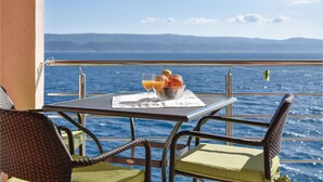 A table with a glass of orange juice, a bowl of fruit, and a menu on a balcony overlooking the sea. - 1 bedroom beach front apartment in Stanici (Stanici)