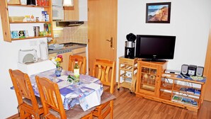 Ett kompakt bostadsutrymme med en matplats, ett litet kök och en plats för underhållning.