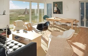 Ett modernt vardagsrum med ett stort fönster, en matplats och en bekväm sittgrupp.