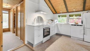A modern kitchen with white cabinetry, a built-in oven, and a stove. There is a window with a view of greenery outside. - 2 bedroom gorgeous home in Silkeborg (Silkeborg)