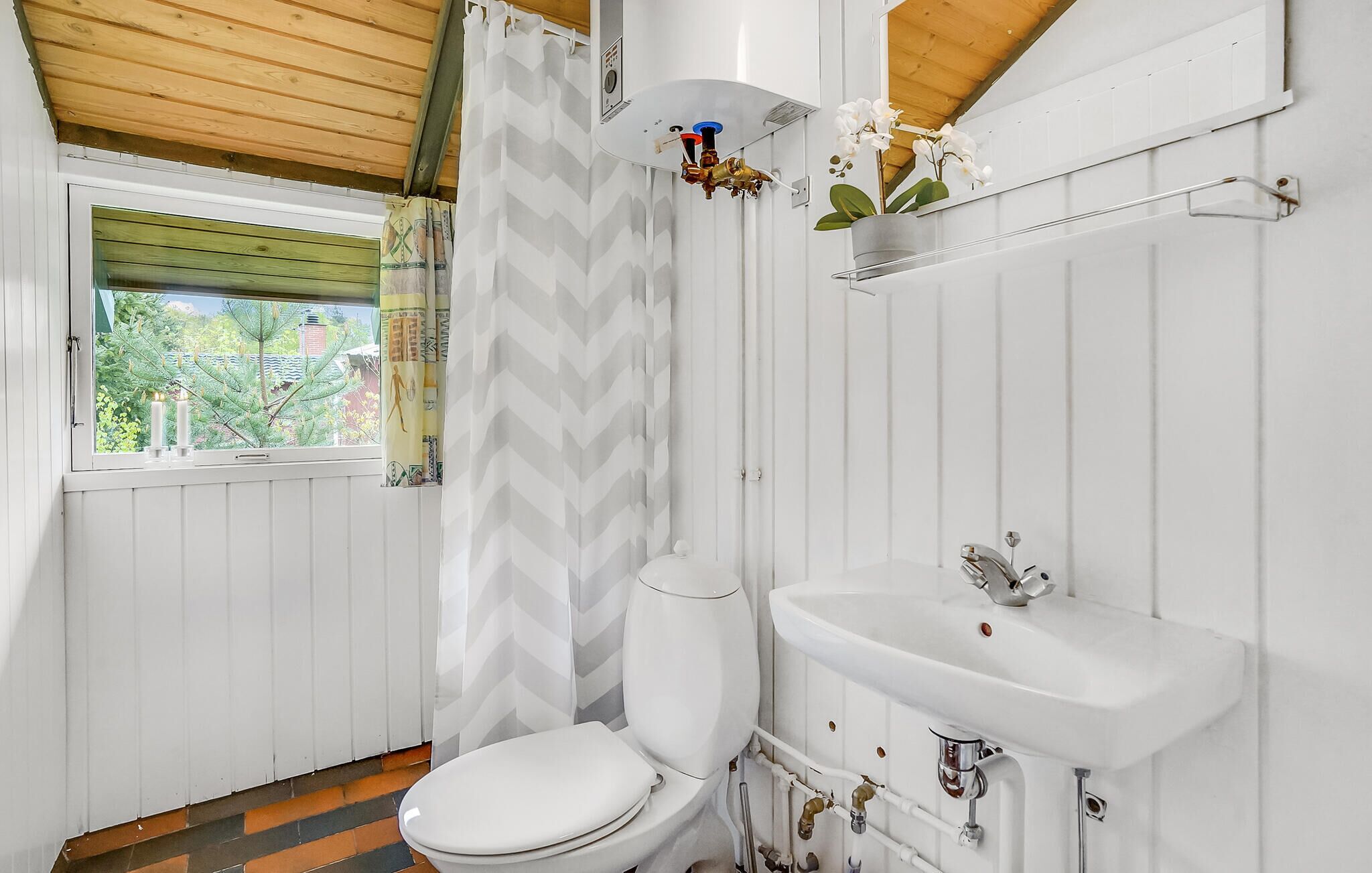Ein kleines, kompaktes Badezimmer mit Toilette, Waschbecken und Duschbereich, alles in Weiß.
