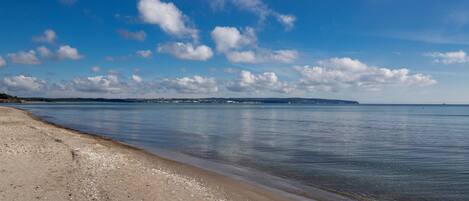 Een strand met een heldere lucht en rustig water.