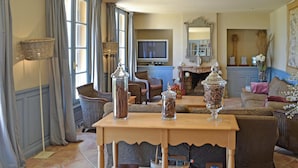 A cozy living room with wicker furniture, a wooden coffee table, and a television in the background. - Lovely home in Béziers (Béziers)