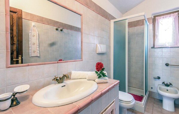 Un baño con un espejo grande, lavamanos, inodoro y ducha.