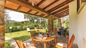 An outdoor patio with a wooden table and chairs, surrounded by stone pillars and a view of a lush garden. - Beautiful home in Gavorrano GR with WiFi (Gavorrano GR)